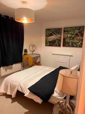 a bedroom with a bed and a table with a lamp at Beautiful Home at the Heart of Colchester Great for Commuters or Professionals in Colchester