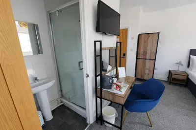 a bathroom with a sink and a blue chair at Free Parking-Modern Rooms in Central Cambridge Guest House by Luxiety Stays Near University in Cambridge