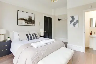 a white bedroom with a large bed and a bench at Cambridge City Centre by Luxiety Stays Stylish Rooms, Prime Location & Wi-Fi in Cambridge
