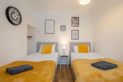 two beds in a room with a clock on the wall at 4 BDR I sleeps 8 I Wi-FI I Free Parking I Central in Chesterton