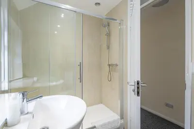 a white bathroom with a shower and a toilet at 4 BDR I sleeps 8 I Wi-FI I Free Parking I Central in Chesterton