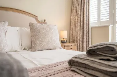 a bedroom with a white bed with a pillow and a window at Woodland Lodge, Aldeburgh in Aldeburgh