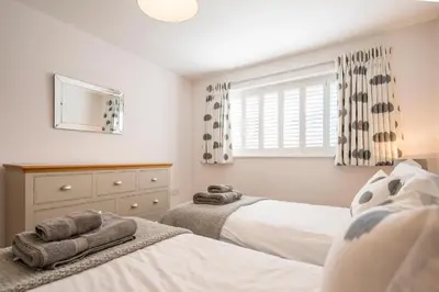 a bedroom with two beds and a dresser and a window at Woodland Lodge, Aldeburgh in Aldeburgh