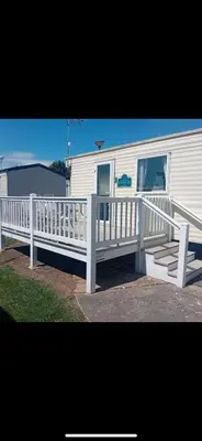 a white house with a porch and a white fence at Seawick Staycay in Saint Osyth