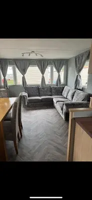 a living room with a long couch and a table at Seawick Staycay in Saint Osyth