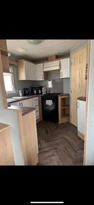 a kitchen with white cabinets and a black stove at Seawick Staycay in Saint Osyth