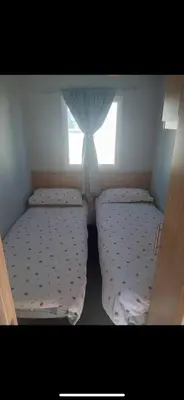 two beds in a small room with a window at Seawick Staycay in Saint Osyth