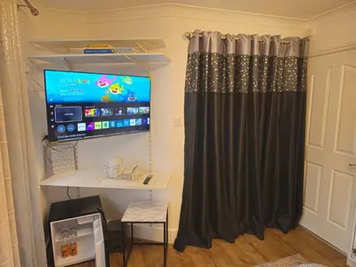 a room with a desk and a tv and a curtain at Meredith House, Ipswich in Ipswich