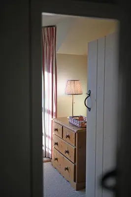 a bedroom with a dresser with a lamp on it at Pilots House Aldeburgh in Aldeburgh