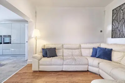 a white couch in a living room with blue pillows at The Opulent Property Project Southend Beach House Sleeps 8 Free Parking x 2 Perfect for Contractors 4 King Beds or 8 Single Beds in Southend-on-Sea