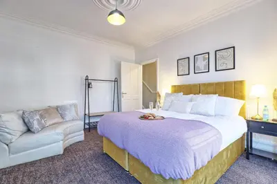 a bedroom with a large bed and a couch at The Opulent Property Project Southend Beach House Sleeps 8 Free Parking x 2 Perfect for Contractors 4 King Beds or 8 Single Beds in Southend-on-Sea