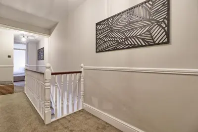 a staircase in a home with a painting on the wall at The Opulent Property Project Southend Beach House Sleeps 8 Free Parking x 2 Perfect for Contractors 4 King Beds or 8 Single Beds in Southend-on-Sea