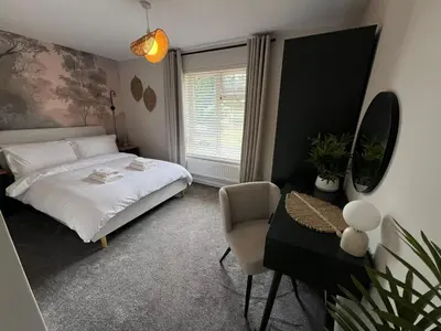 a bedroom with a bed and a chair and a window at Stunning and Peaceful 2 bed Flat 10 mins from Stansted Airport in Stansted Mountfitchet