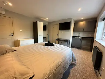 a bedroom with a large bed and a kitchen at Abbey House in Waltham Abbey