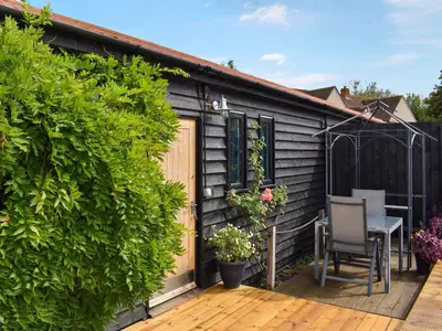 a small house with a wooden deck and a table at Saddlers - Uk50519 in Ovington