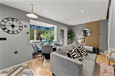 a living room with a couch and a clock on the wall at Sleek & Stylish House in Cambridge - Sleeps 6 in Milton