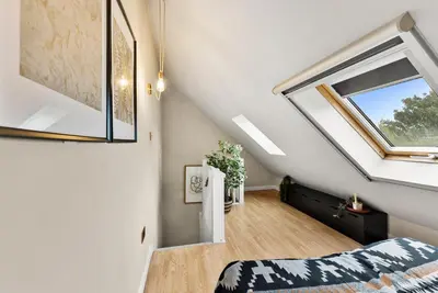 a attic bedroom with a window and a bed at Sleek & Stylish House in Cambridge - Sleeps 6 in Milton