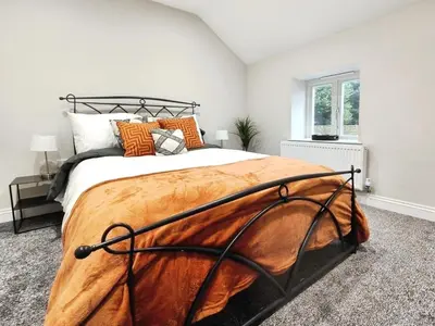 a bedroom with a large bed with orange pillows at Stylish 2-Bed Home Near A11 in Thetford