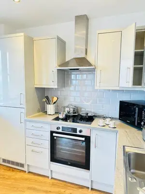 a kitchen with white cabinets and a stove top oven at Gorgeous two bedroom luxury Apartment sleeps 6 in Brentwood