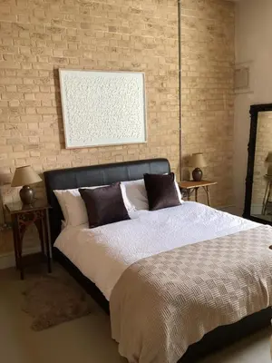a bedroom with a bed and a brick wall at Basils Bolthole in Darsham