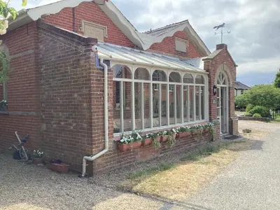 a brick building with windows and potted plants on it at Basils Bolthole in Darsham