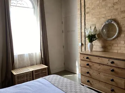 a bedroom with a dresser and a mirror and a bed at Basils Bolthole in Darsham