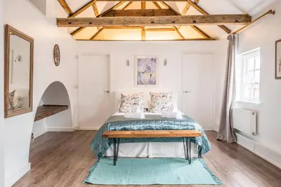 a bedroom with a bed with a blue rug at The Loft, Bungay in Bungay