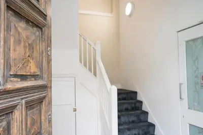 a stairwell with a wooden door and a staircase with white walls at The Loft, Bungay in Bungay