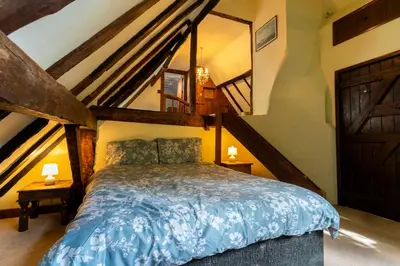 a bedroom with a bed with blue comforter at Group Stays 600-Year-Old Barn, sleeps 11 in Great Parndon