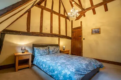 a bedroom with a bed and two night stands at Group Stays 600-Year-Old Barn, sleeps 11 in Great Parndon