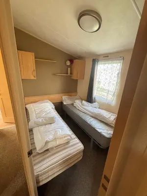 a small room with two beds and a window at Singh&Leite Family L6 in Saint Osyth