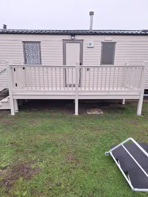 a house with a porch with a bench on the grass at Singh&Leite Family L6 in Saint Osyth