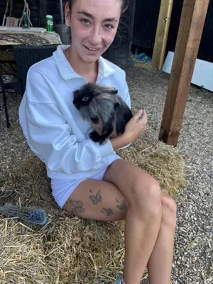 a woman sitting on hay holding a baby chicken at Goldings detached Barn farm stay in Hertford