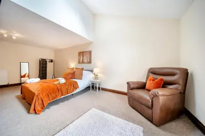 a bedroom with a bed and a leather chair at 4 Bdr House with TV, Wifi, near Thetford town in Thetford