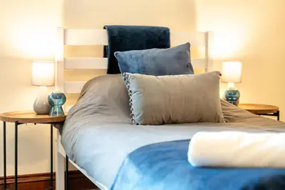 a bed with blue sheets and two lamps on tables at 4 Bdr House with TV, Wifi, near Thetford town in Thetford