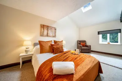 a bedroom with a large bed with an orange blanket at 4 Bdr House with TV, Wifi, near Thetford town in Thetford