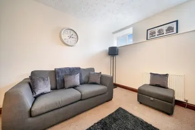 a living room with a couch and a clock on the wall at 4 Bdr House with TV, Wifi, near Thetford town in Thetford