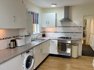 a kitchen with white cabinets and a washer and dryer at Southend city Escape, SS1, High St and beach are steps away in Southend-on-Sea