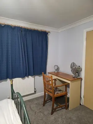 a bedroom with a desk and a bed and a blue curtain at Essex studio x2 in Hythe