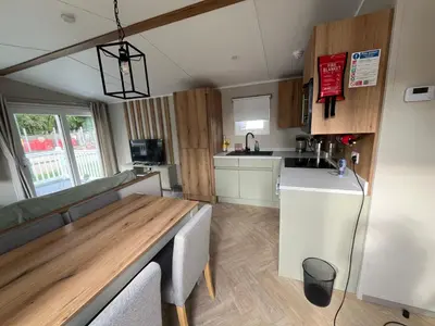 a kitchen and living room with a table and a counter at The Orchards modern caravan in Saint Osyth