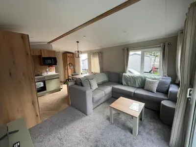 a living room with a couch and a table at The Orchards modern caravan in Saint Osyth