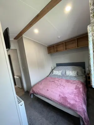 a bedroom with a bed with a pink blanket at The Orchards modern caravan in Saint Osyth