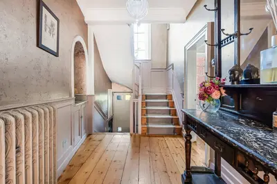 a hallway with stairs and a vase of flowers on a counter at 6 Bedroom - Luxury - Cinema Room in Hertford