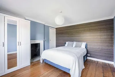 a bedroom with a large bed with a wooden headboard at 6 Bedroom - Luxury - Cinema Room in Hertford