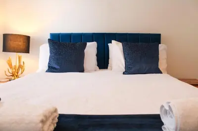 a bedroom with a bed with blue pillows at Stylish Essex Apartment, Balcony & Scenic Views in Harlow