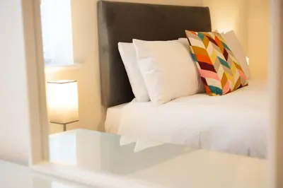 a bedroom with a bed with a pillow and a lamp at 1 The Royal Serviced Apartments, Harwich SuperKing Bed, Parking, Fast WiFi in Parkeston