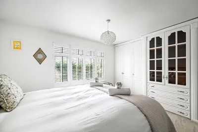 a white bedroom with a large white bed and windows at Stylish 3-Bed Home Close to Stansted Airport in Stansted Mountfitchet