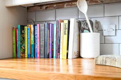 a row of books sitting on a shelf at Stylish 3-Bed Home Close to Stansted Airport in Stansted Mountfitchet