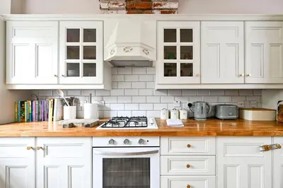 a kitchen with white cabinets and a stove top oven at Stylish 3-Bed Home Close to Stansted Airport in Stansted Mountfitchet
