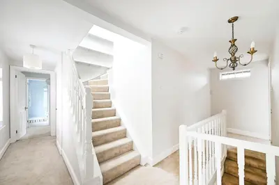 a white staircase in a white home with a chandelier at Stylish 3-Bed Home Close to Stansted Airport in Stansted Mountfitchet